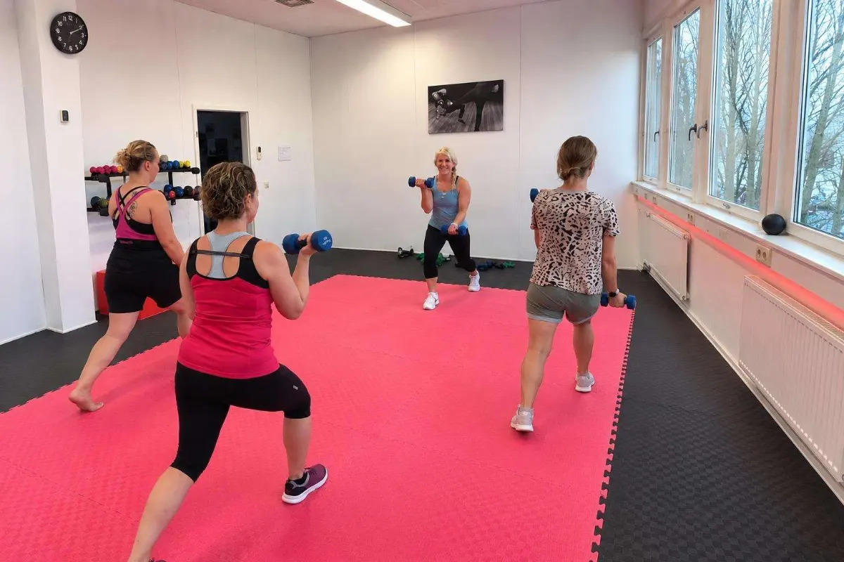 Trainerin und Teilnehmerinnen beim Ausfallschritt mit Kurzhanteln im Full Body Workout